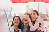 Tourists with umbrella taking selfie, London, UK