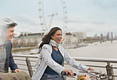 Couple bike riding on bridge, London, UK