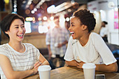 Laughing women drinking coffee at cafe