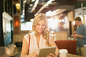 Smiling woman using tablet in cafe