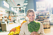 Portrait woman holding bunch of kale in market