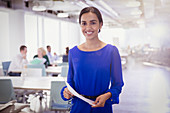Portrait businesswoman with paperwork in office