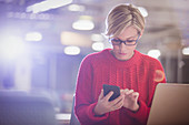 Businesswoman working late at laptop, texting
