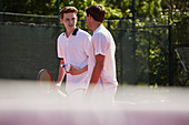 Male tennis players with tennis rackets talking