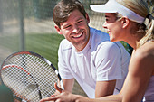 Smiling tennis players resting and talking