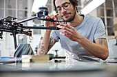 Male designer with tattoos assembling drone