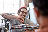 Smiling designer with tattoos assembling drone