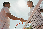Young tennis players handshaking at net