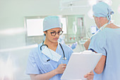 Female surgeon reviewing paperwork on clipboard