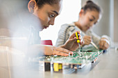 Focused girl student assembling circuit board
