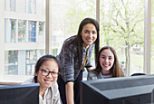 Teacher and girl students researching at computer