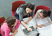 Female teacher helping girl students researching