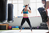 Determined female boxers kickboxing in gym