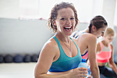 Portrait laughing woman drinking water at gym