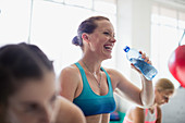 Laughing woman drinking water at gym