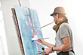 Male artist painting at easel in art studio