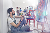 Male painter painting, examining painting