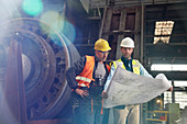 Engineers reviewing blueprints in steel factory
