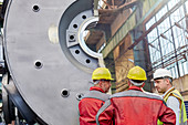 Male workers talking in steel factory