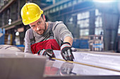 Focused male worker examining steel in factory