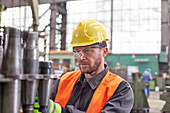 Focused worker examining steel parts