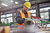 Male worker assembling steel part in factory
