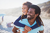 Laughing father piggybacking daughter