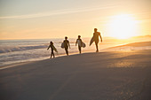 Silhouette family surfers walking with surfboards