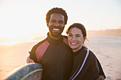 Portrait multi-ethnic couple with surfboard