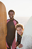 Portrait father and son with surfboards