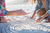 Mother and daughter placing seashell in sand