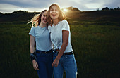 Portrait happy teenage sisters in rural field