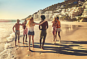 Young couple friends walking on sunny summer beach