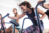 Smiling, playful woman using elliptical bike