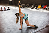 Young woman stretching, using kettle bell