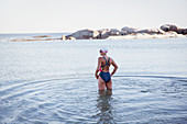 Female swimmer standing, wading in ocean