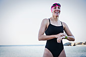 Smiling female swimmer adjusting smart watch
