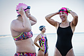 Smiling swimmers adjusting swimming caps