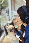 Pensive woman drinking coffee, listening to music
