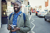 Smiling male tourist with camera on urban street