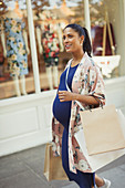 Pregnant woman walking along storefront