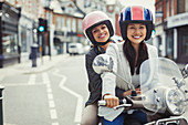Smiling women riding motor scooter