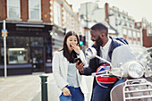 Young couple laughing, using cell phone