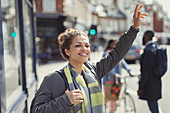 Smiling woman hailing taxi on sunny urban street
