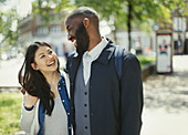 Affectionate couple laughing in sunny urban park