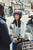 Smiling woman in helmet on motor scooter