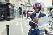Smiling businessman on motor scooter texting