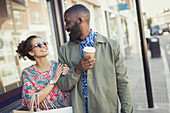 Smiling couple with coffee walking arm in arm