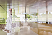 Scientist in clean suit using tablet at window