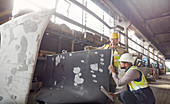 Steelworkers examining steel part in steel mill